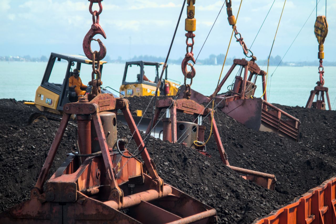 The Art of Drawing Readers In: Your attractive post title goes here Heavy machinery loading coal at a port with a clear sky reflecting on the water.