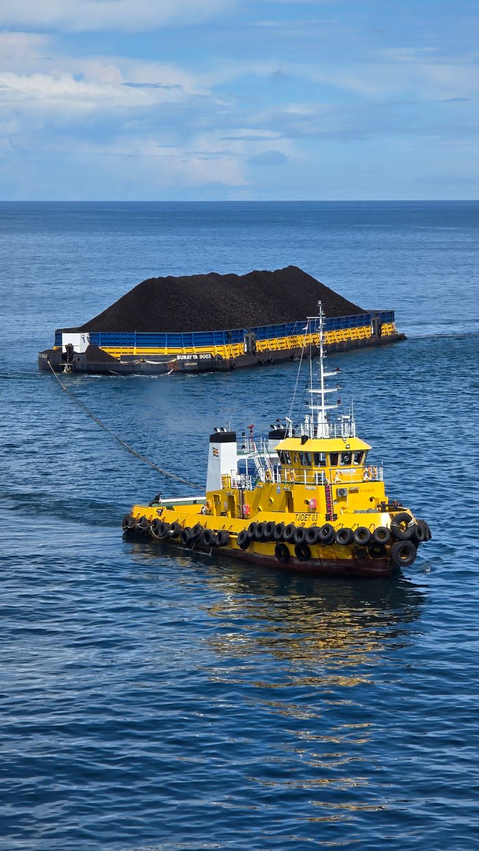 Mastering the First Impression: Your intriguing post title goes here A yellow tugboat hauls a coal barge on calm waters in Indonesia, showcasing maritime industry.